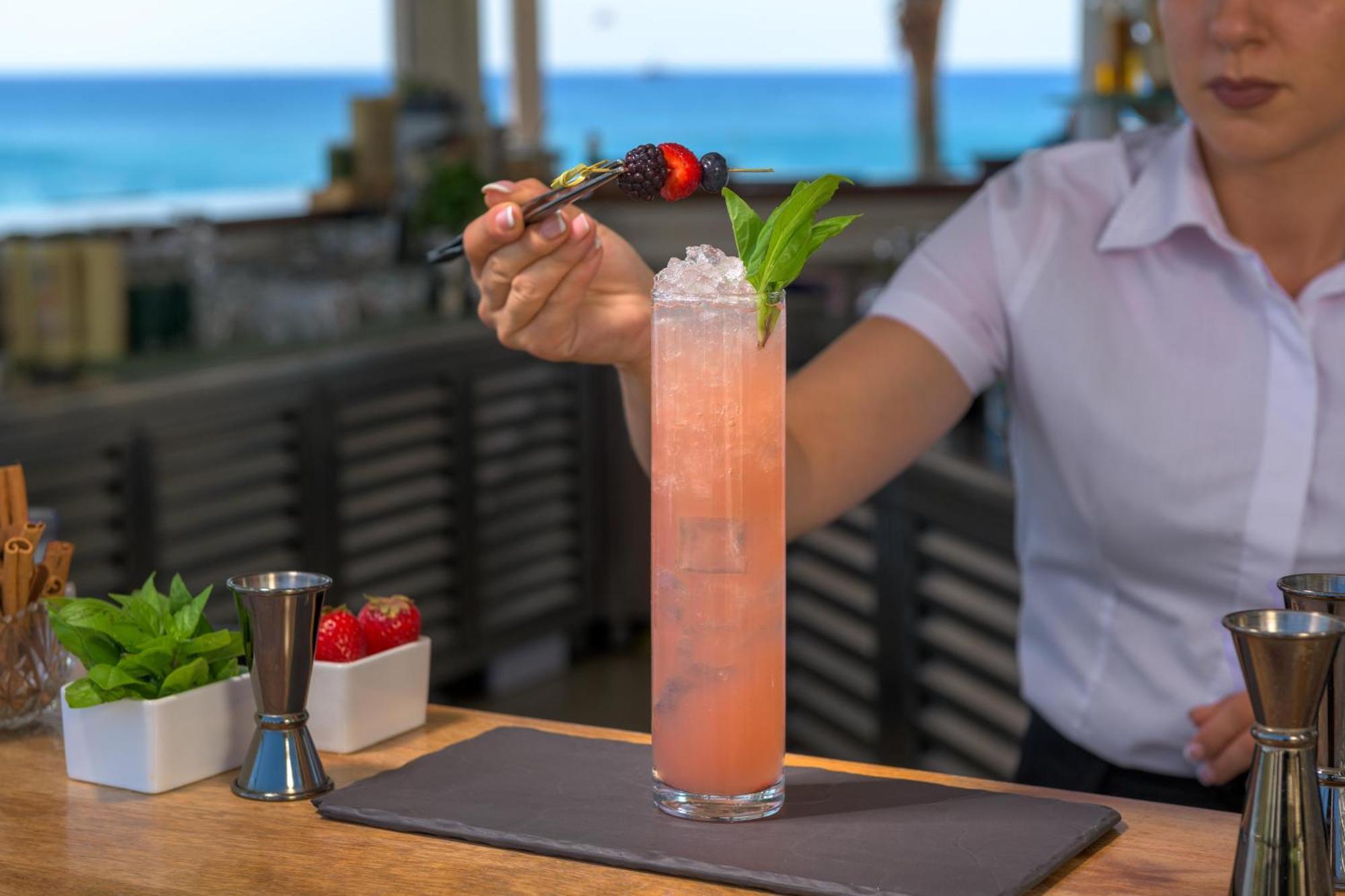 Rodos Palladium Leisure & Wellness Kallithea  Exterior photo A bartender garnishes a cocktail with a fruit skewer.